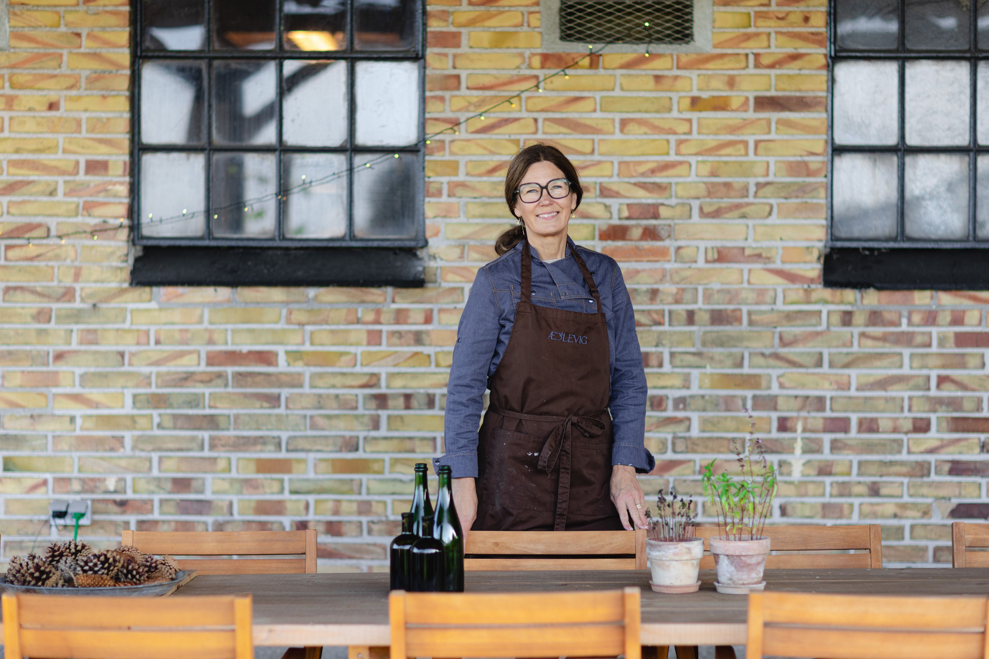 Vibeke at the long table under the covered terrace at Æblevig in Vig